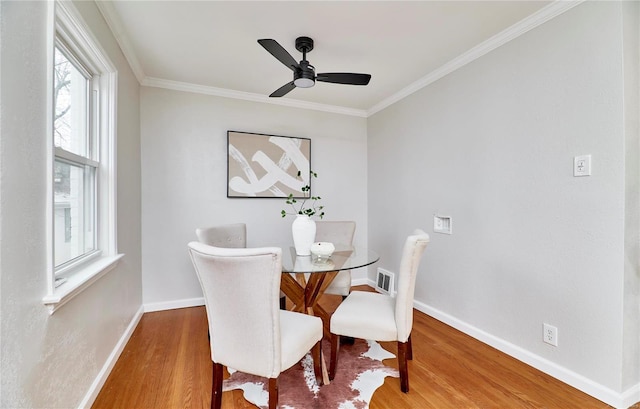 dining room with ornamental molding, wood finished floors, and baseboards