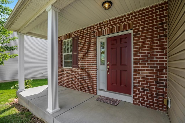 entrance to property with covered porch and brick siding
