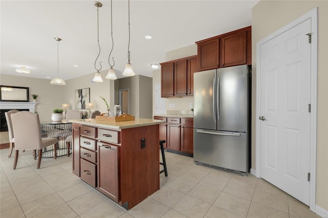 kitchen with freestanding refrigerator, a kitchen island, light tile patterned flooring, and hanging light fixtures