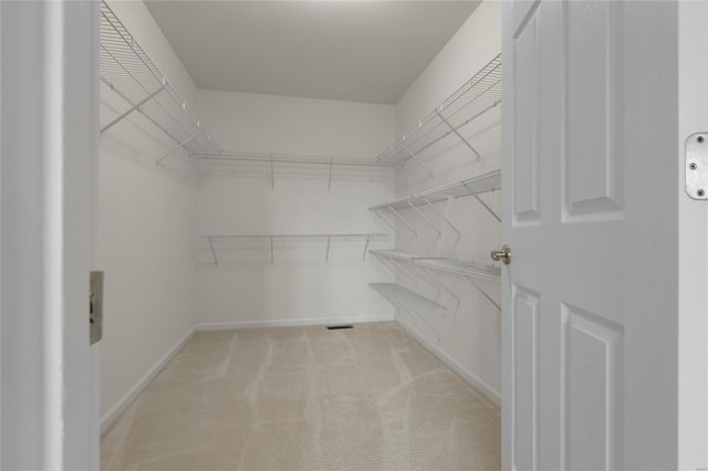 spacious closet featuring visible vents and light carpet