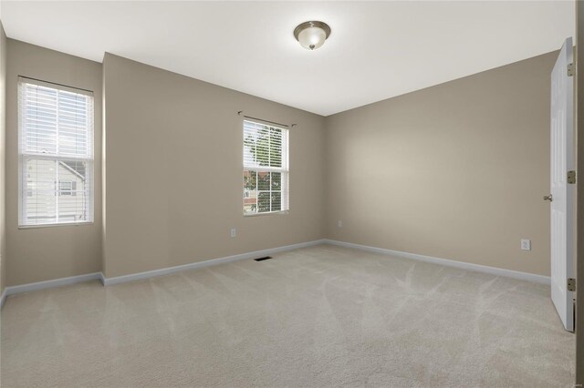 unfurnished room with baseboards, visible vents, and light carpet