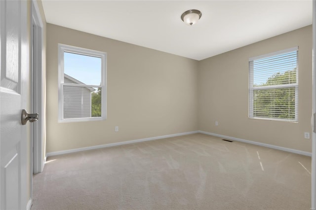 spare room featuring baseboards, light carpet, and visible vents