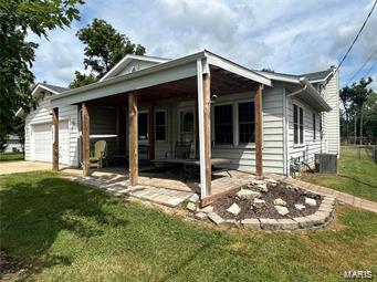 view of front of house featuring a garage, central AC, a front lawn, and concrete driveway