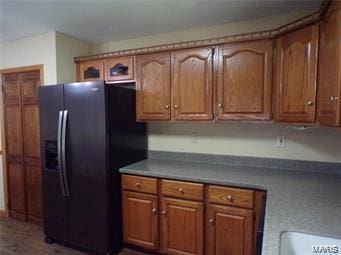 kitchen featuring brown cabinetry and black fridge with ice dispenser