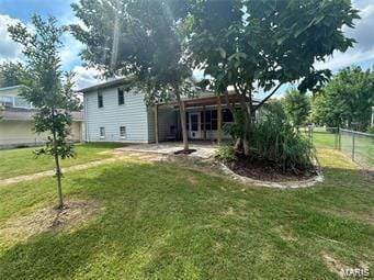 rear view of house with fence, a lawn, and a patio