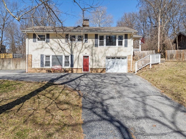 view of front of home with driveway, fence, a chimney, and an attached garage