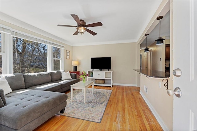 living room with light wood-style floors, ceiling fan, and baseboards