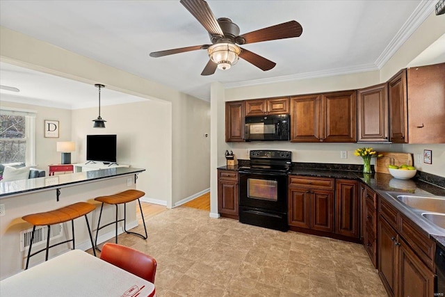 kitchen featuring a sink, a kitchen breakfast bar, black appliances, dark countertops, and decorative light fixtures