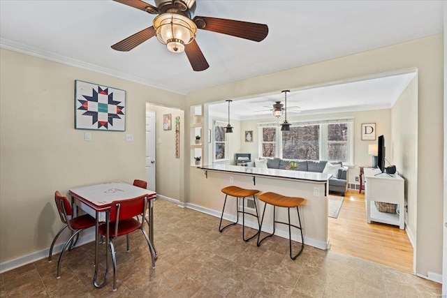 dining room with crown molding, a ceiling fan, and baseboards