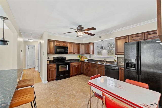 kitchen featuring dark countertops, hanging light fixtures, a sink, ceiling fan, and black appliances