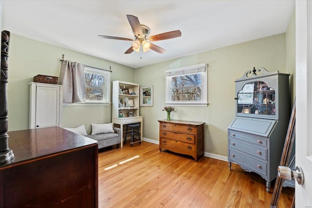 home office with light wood-style flooring, baseboards, and a ceiling fan