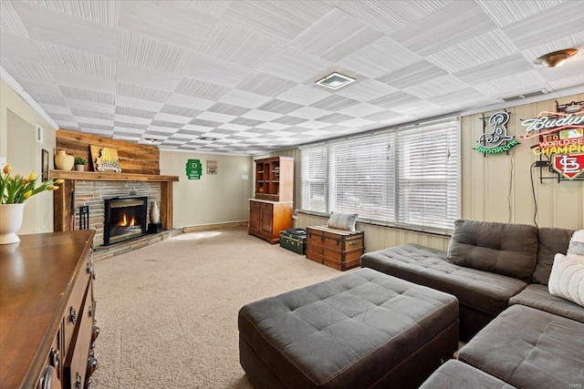 living area featuring visible vents, light colored carpet, and a stone fireplace