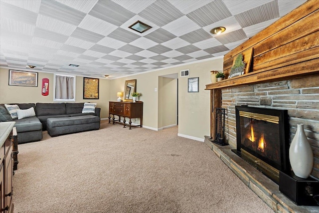 carpeted living room featuring a stone fireplace and baseboards