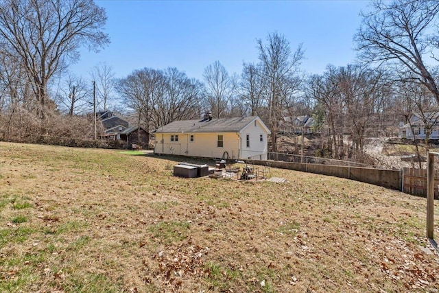 rear view of property with an outdoor fire pit, fence, and a yard