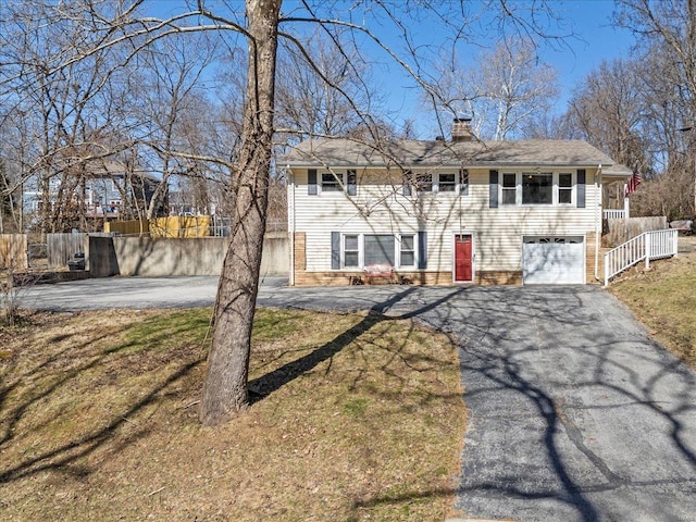 view of front of property featuring an attached garage, a chimney, fence, and aphalt driveway