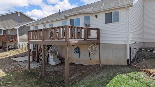 rear view of house featuring a wooden deck, fence, and a shingled roof