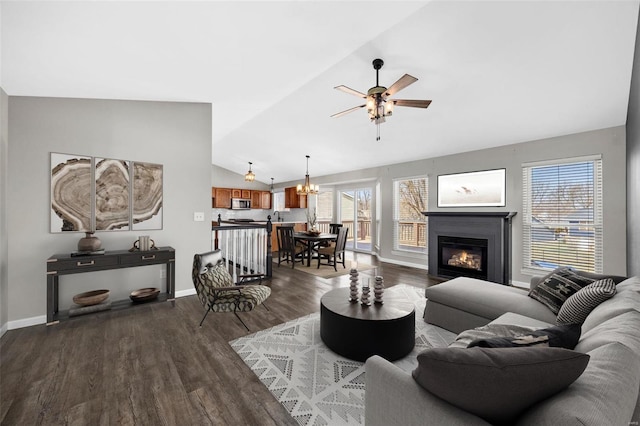 living room with dark wood finished floors, vaulted ceiling, a healthy amount of sunlight, and ceiling fan