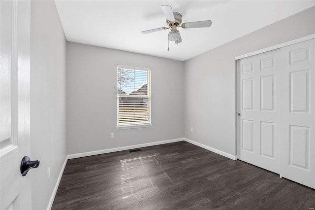 unfurnished bedroom with visible vents, ceiling fan, baseboards, and dark wood-style flooring