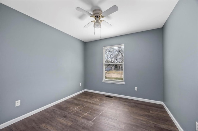 empty room with baseboards, dark wood finished floors, and a ceiling fan