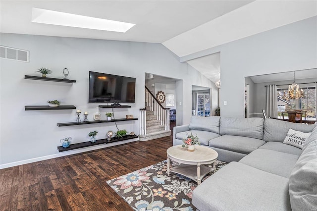 living area featuring visible vents, a chandelier, stairs, vaulted ceiling with skylight, and wood finished floors