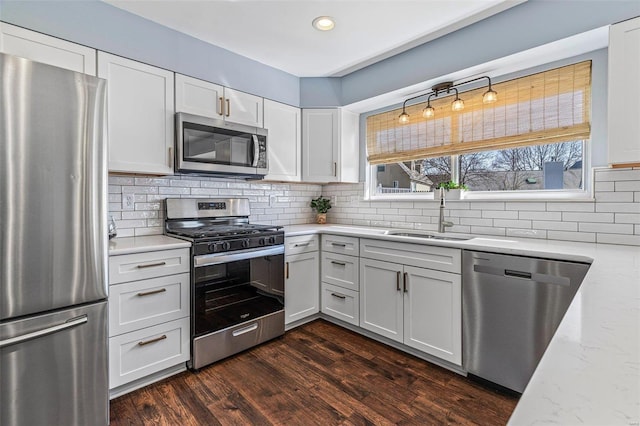 kitchen featuring dark wood-style floors, a sink, white cabinets, appliances with stainless steel finishes, and backsplash