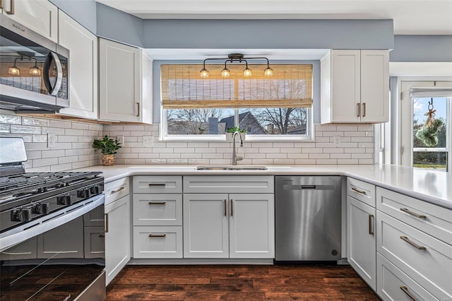 kitchen featuring dark wood finished floors, light countertops, decorative backsplash, stainless steel appliances, and a sink