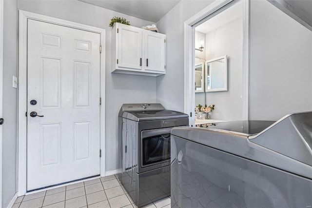 clothes washing area with washer and dryer, light tile patterned flooring, cabinet space, and baseboards