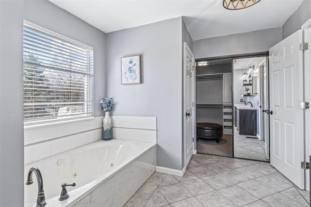 bathroom featuring tile patterned floors, baseboards, vanity, and a whirlpool tub