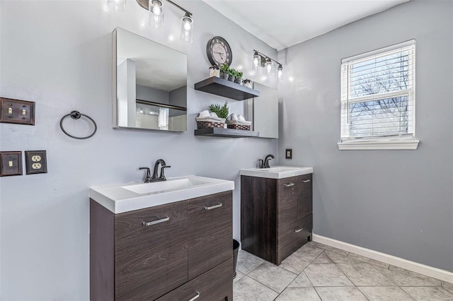 full bath featuring tile patterned flooring, two vanities, baseboards, and a sink