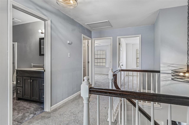 corridor with baseboards, carpet, attic access, an upstairs landing, and a sink