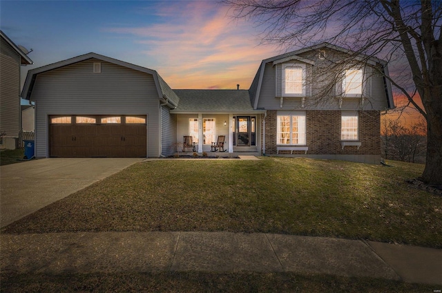 colonial inspired home featuring a garage, a gambrel roof, concrete driveway, and a front yard