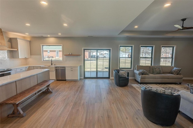 living area with baseboards, light wood-style flooring, ceiling fan, a tray ceiling, and recessed lighting