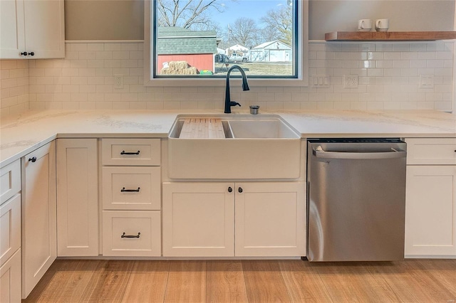 kitchen with dishwasher, a sink, light wood-style flooring, and white cabinetry