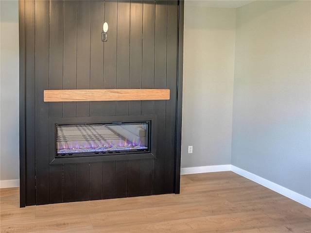 interior details featuring a large fireplace, baseboards, and wood finished floors