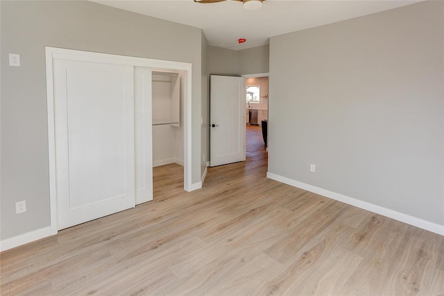 unfurnished bedroom featuring a closet, baseboards, and wood finished floors