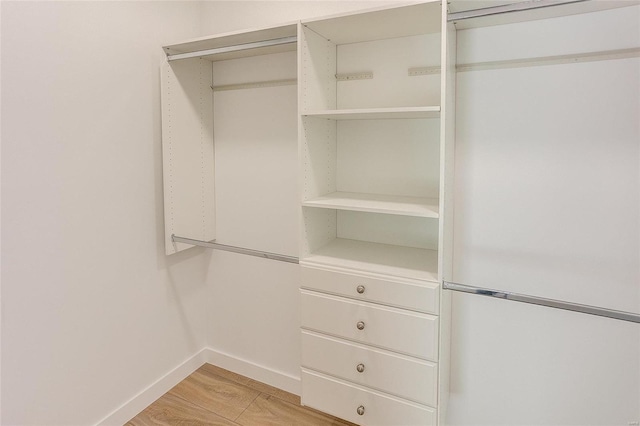 walk in closet with light wood finished floors