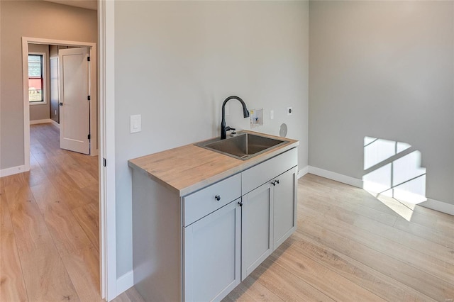 kitchen featuring a sink, light wood-style flooring, and baseboards