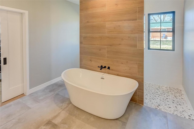 full bath featuring a freestanding tub, wooden walls, baseboards, and walk in shower