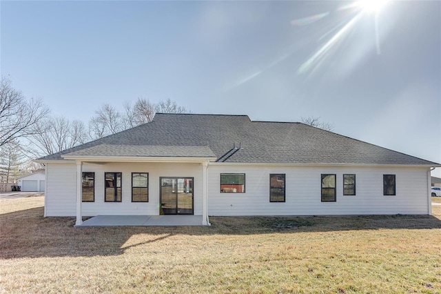 back of property featuring roof with shingles, a lawn, and a patio area