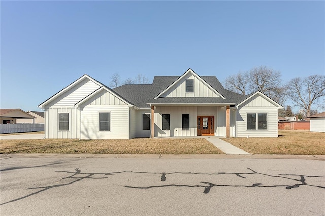 modern farmhouse style home featuring board and batten siding, a porch, a shingled roof, and fence