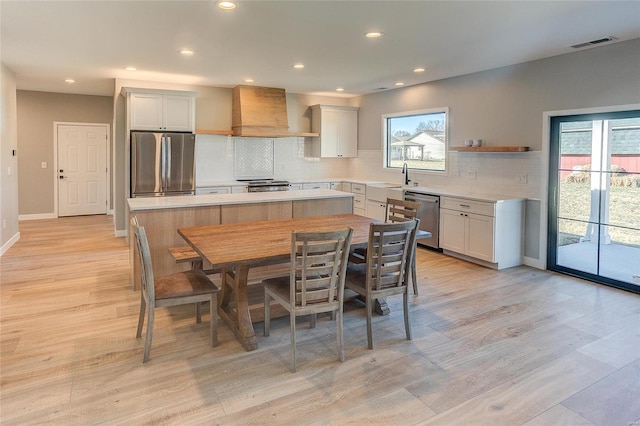 kitchen featuring a sink, visible vents, appliances with stainless steel finishes, wall chimney range hood, and open shelves