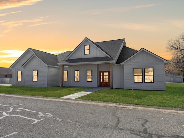 modern inspired farmhouse with roof with shingles, board and batten siding, and a front yard