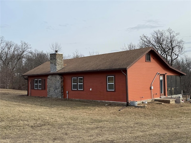 view of home's exterior featuring a shingled roof, a lawn, and a chimney