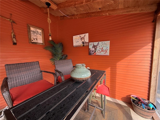 living area with wooden ceiling, beam ceiling, and wooden walls