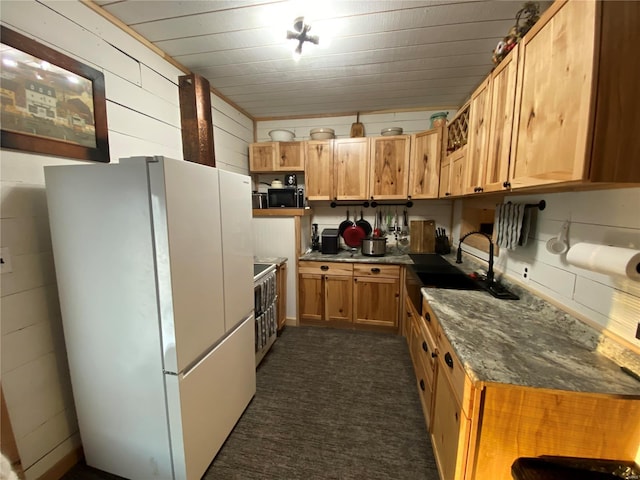 kitchen with freestanding refrigerator, a sink, wooden walls, and open shelves