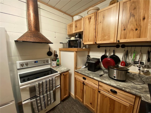 kitchen with white appliances, wooden walls, and wall chimney exhaust hood