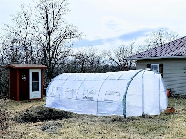 view of yard featuring a greenhouse and an outdoor structure