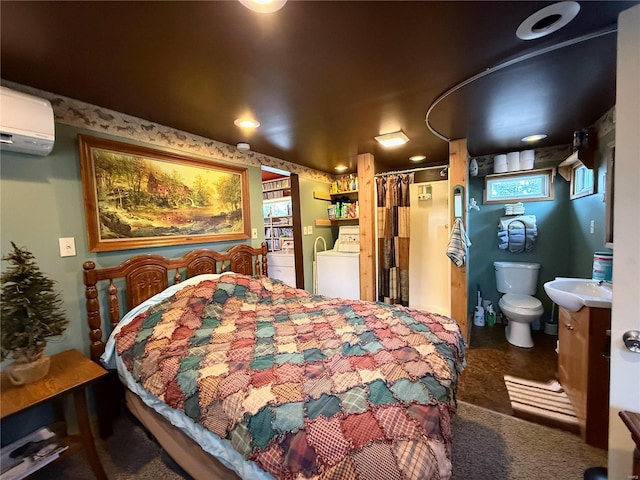 bedroom featuring a wall unit AC, washing machine and dryer, and a sink