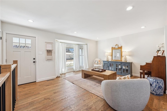 living room featuring recessed lighting, visible vents, baseboards, and light wood finished floors