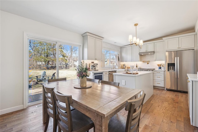 dining space with a notable chandelier, light wood-style flooring, and baseboards